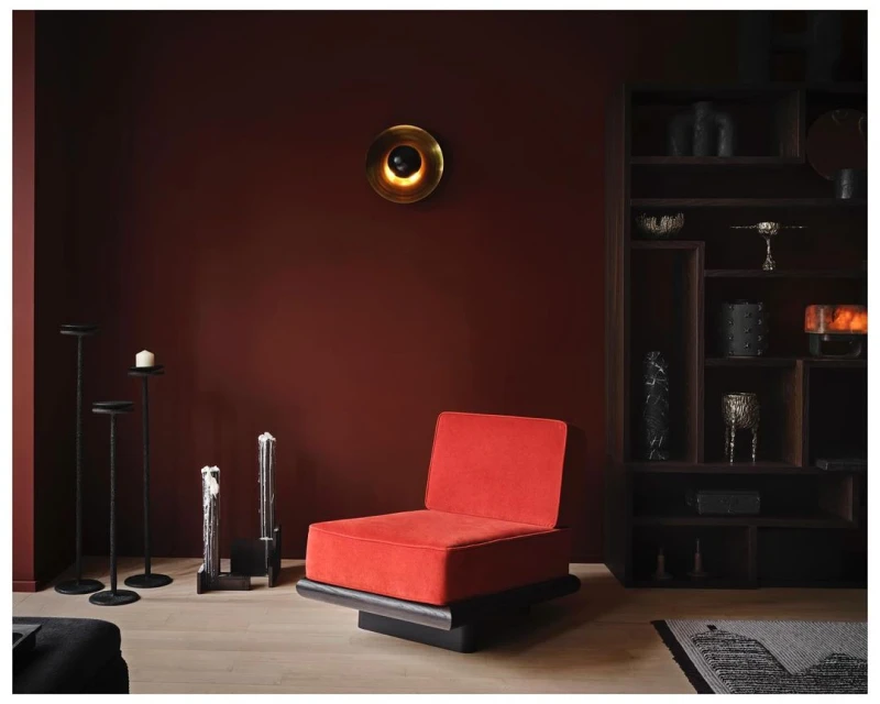 Red accent chair in a modern room with minimalist decor, warm lighting, and a red wall, creating a cozy and stylish interior.