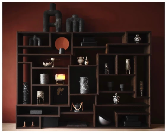 Interior view of a wooden bookcase with decorative objects against a dark red wall, creating a warm, inviting aesthetic.