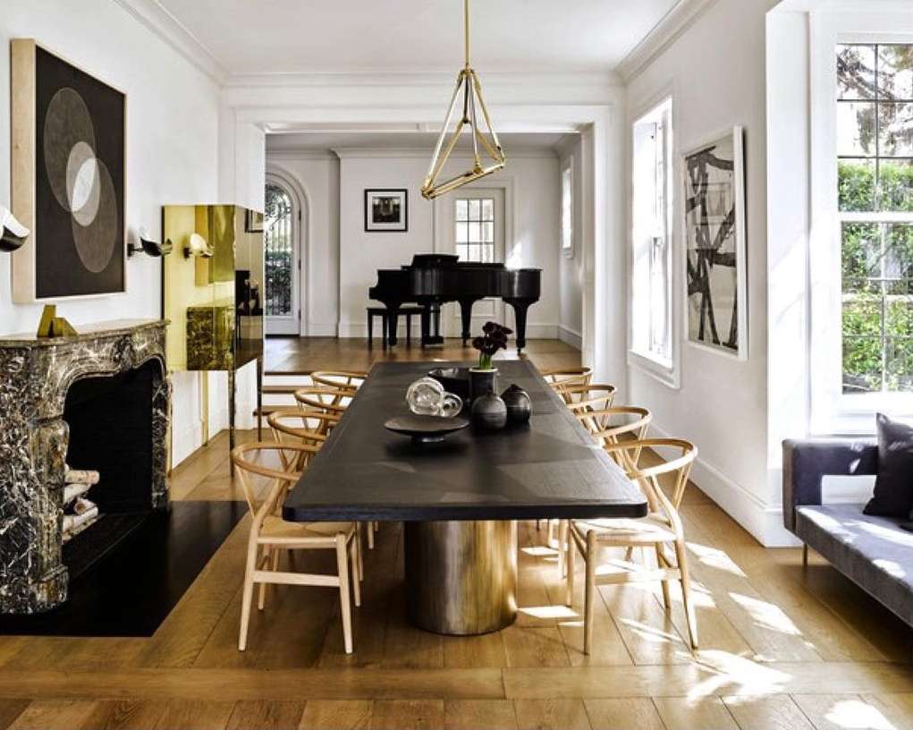 Long wooden dining table set with modern dishware, surrounded by chairs in a bright, minimalist dining room with hardwood floors.