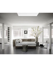 Modern interior living space with a grey daybed, dark geometric side table, and minimalist black sling chair.