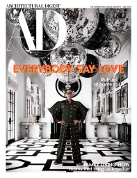 RuPaul standing in an opulent high-ceilinged room beneath hanging disco balls, photographed by Douglas Friedman for Architectural Digest.