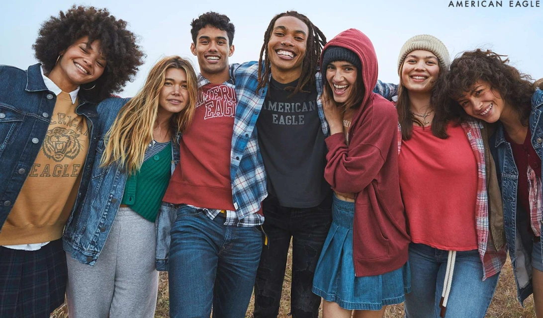 Diverse group of smiling young adults wearing casual clothing. Medium shot of seven people in sweatshirts, jeans, and denim jackets.