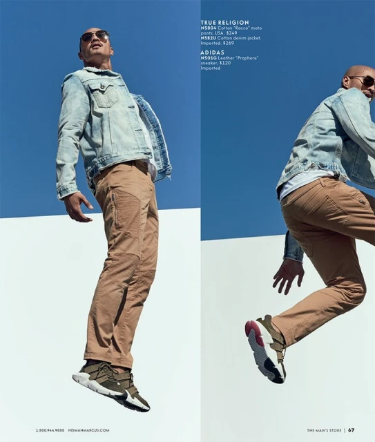 Fashion editorial: Man in denim jacket and tan pants jumps in front of blue and white architecture, showcasing streetwear style.
