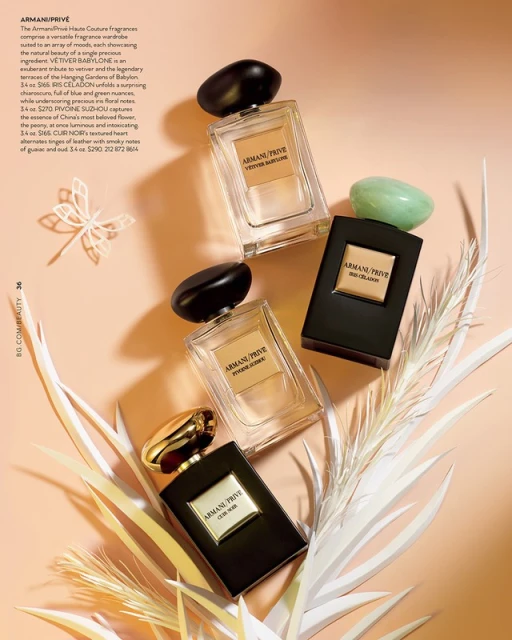 Arrangement of Armani Prive perfume bottles in a still life, presented on a peach-colored surface with decorative botanical elements.