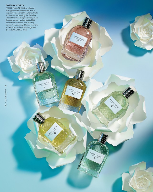 Six Bottega Veneta fragrance bottles are arranged in flower-like positions on a blue background, with white, paper-like floral props.