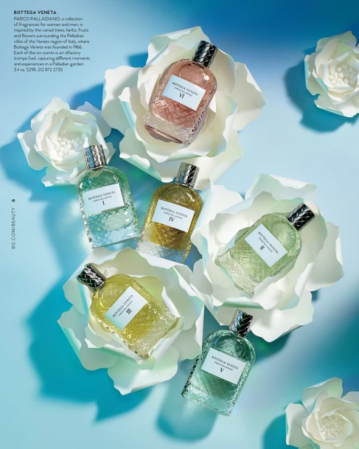Six Bottega Veneta fragrance bottles are arranged in flower-like positions on a blue background, with white, paper-like floral props.