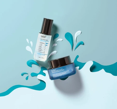 Belif skincare product bottles are displayed on a blue background with paper cutouts resembling water splashes and waves.