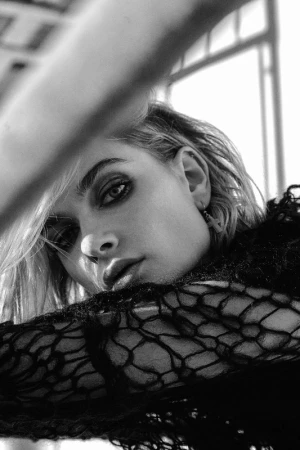 Close-up black and white portrait of a woman wearing a dark patterned lace top and a cross earring in Los Angeles.