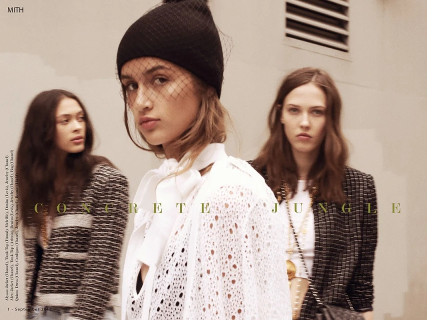 Three women pose in an urban fashion editorial. The model in the foreground wears a black hat and white knit top. Concrete Jungle text overlay.