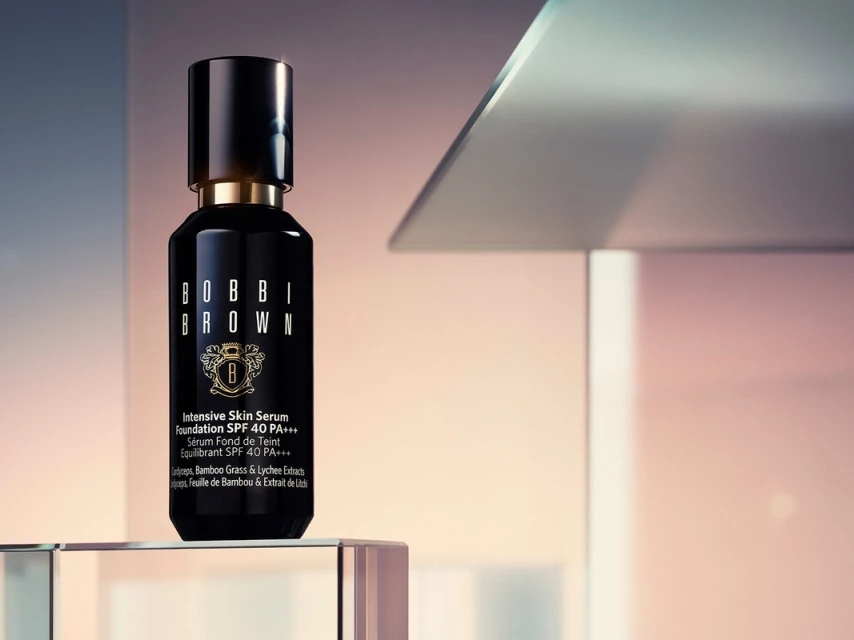 Bobbi Brown Intensive Skin Serum Foundation SPF 40 PA+++ in a black bottle sitting on a clear block against a blurred background.