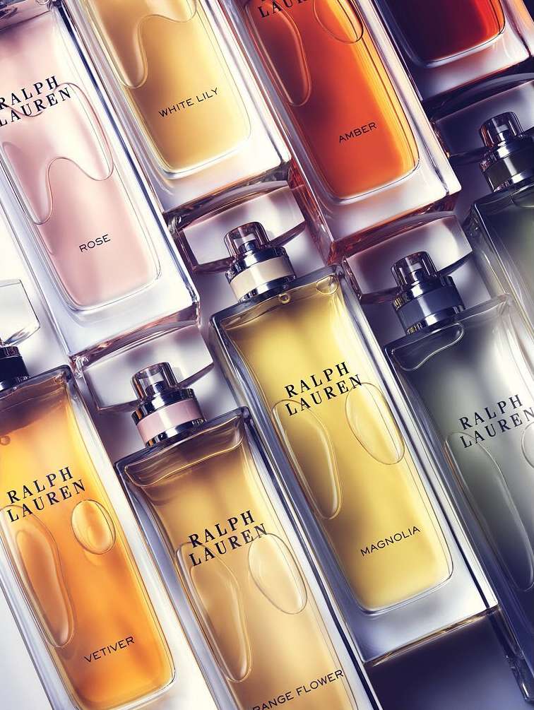 Multiple Ralph Lauren perfume bottles are arranged, showcasing various scents like Rose, White Lily, Amber, Magnolia, Vetiver, and Orange Flower.