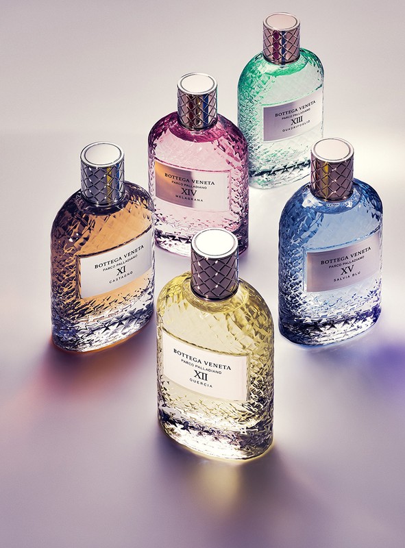 Group of six Bottega Veneta fragrance bottles in various colors: yellow, pink, green, blue, and gold. Close-up studio shot, product focus.