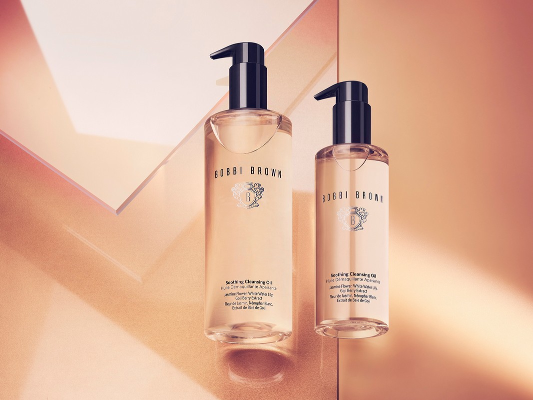 Two Bobbi Brown Soothing Cleansing Oil bottles against a geometric peach and white backdrop, showcasing skincare product photography.
