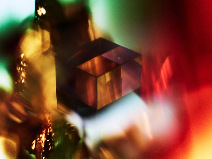 Abstract close-up of translucent cubes refracting light, creating colorful gradients of red, green, and yellow.