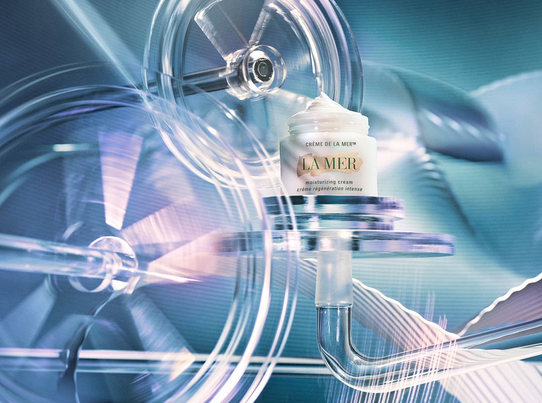La Mer moisturizing cream jar displayed on a transparent mechanism with rotating wheels, showcased in a blue-toned product shot.
