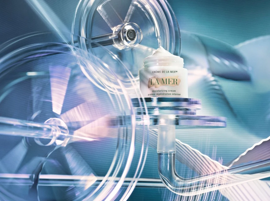 La Mer moisturizing cream jar displayed on a transparent mechanism with rotating wheels, showcased in a blue-toned product shot.
