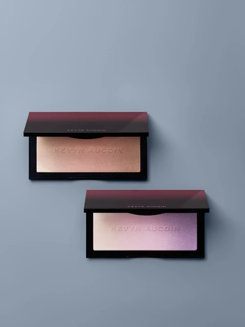 Two Kevyn Aucoin makeup palettes, one with golden shimmer and the other with purple shimmer, are displayed on a grey background.