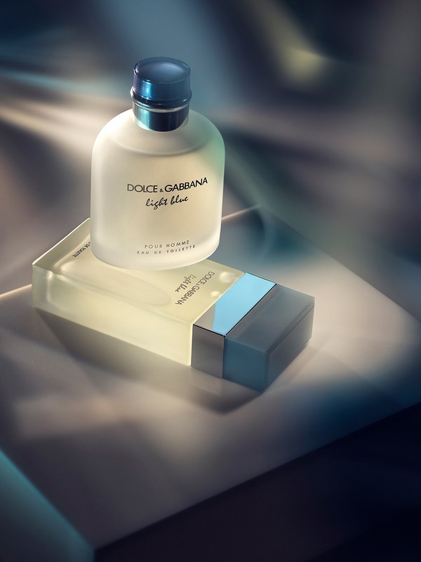 Dolce & Gabbana Light Blue cologne bottle on box, softly lit against a blurred background, showcasing the frosted glass and blue accents.