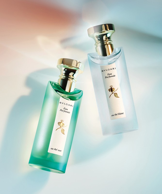 Two Bvlgari perfume bottles on a gradient surface with soft light and colored reflections
