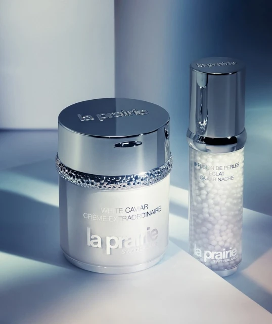 Close-up of La Prairie skincare products: a white cream jar and a clear bottle with pearls, showcasing luxury beauty and skincare.
