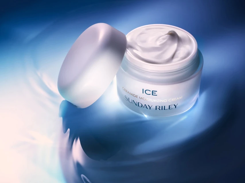 Close-up studio shot of a jar of ceramide moisturizing cream with its lid off on a blue surface, showcasing beauty product.