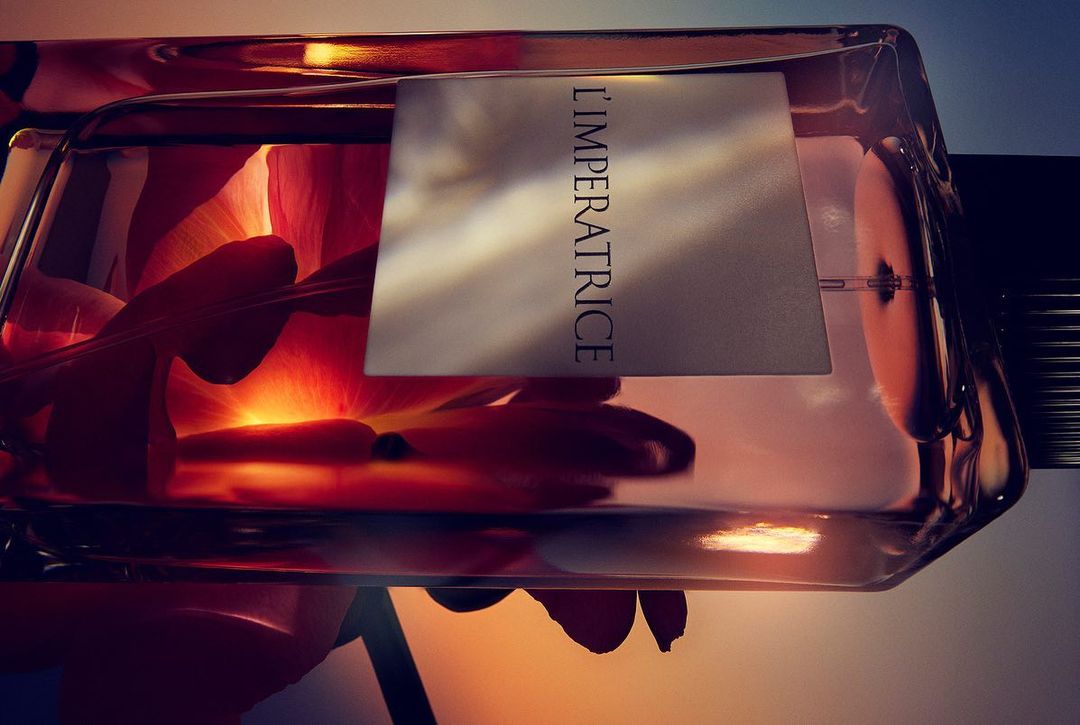 Close-up of a perfume bottle, petals inside, soft lighting, L'IMPERATRICE label, shot horizontally, elegant and luxurious.