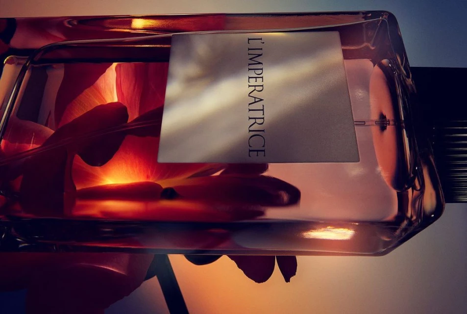 Close-up of a perfume bottle, petals inside, soft lighting, L'IMPERATRICE label, shot horizontally, elegant and luxurious.