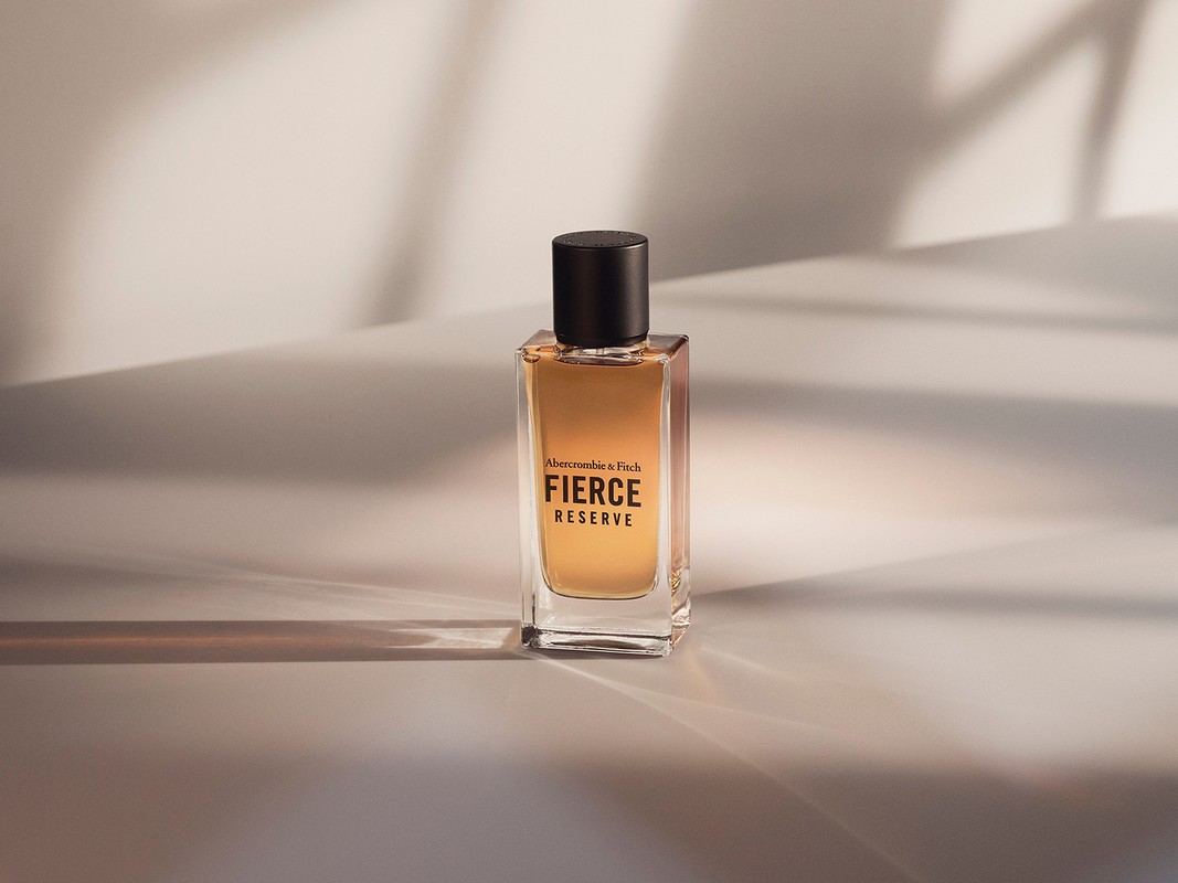 Bottle of Abercrombie & Fitch Fierce Reserve cologne on a cream-colored surface with the shadow of a tree branch behind it.