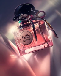 Square glass perfume bottle with a round black cap and patterned silk ribbon by Fabian Öhrn