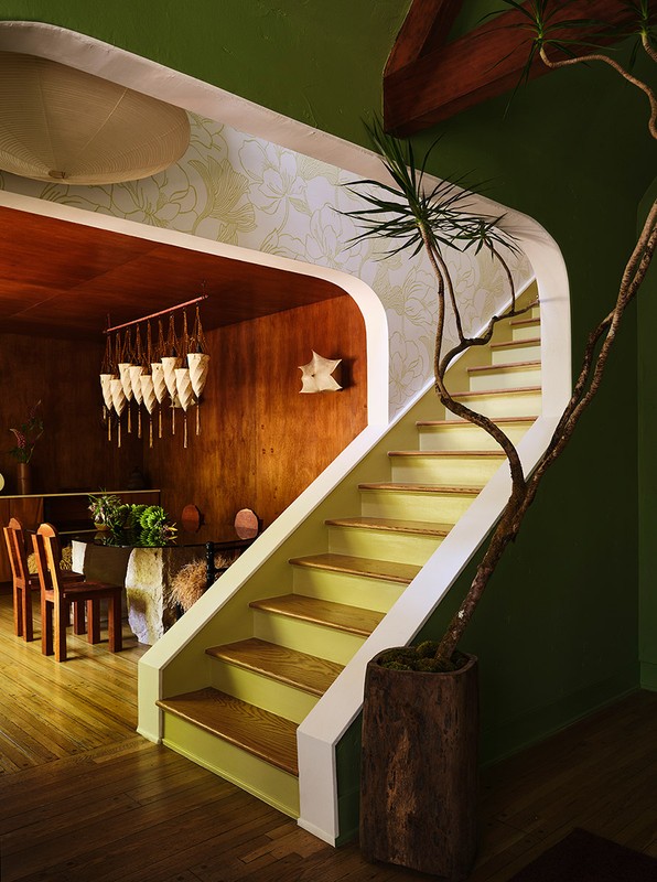 A staircase with yellow steps ascends in a home interior featuring a potted plant, wooden accents, and earth-tone color palette.