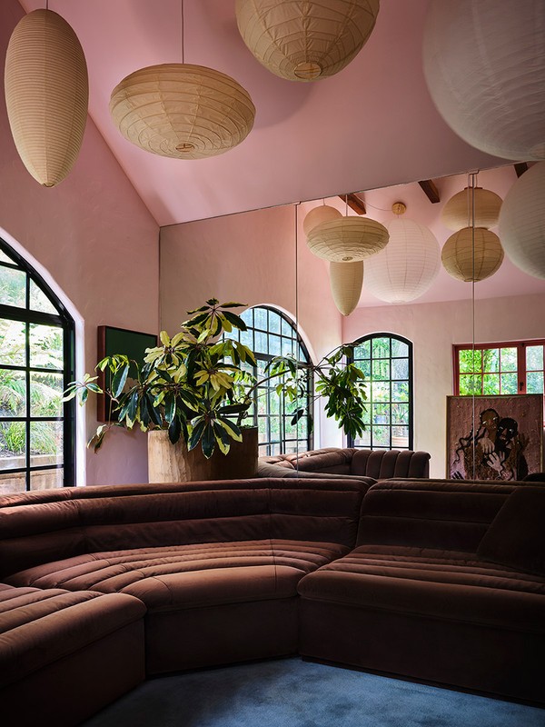 Brown sectional sofa in a living room with paper lanterns hanging from the ceiling, natural light from arched windows, and green plants.