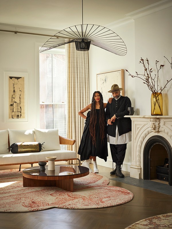 Elegant interior shot of a couple posing in a living room featuring a unique light fixture, modern furniture, and neutral tones.