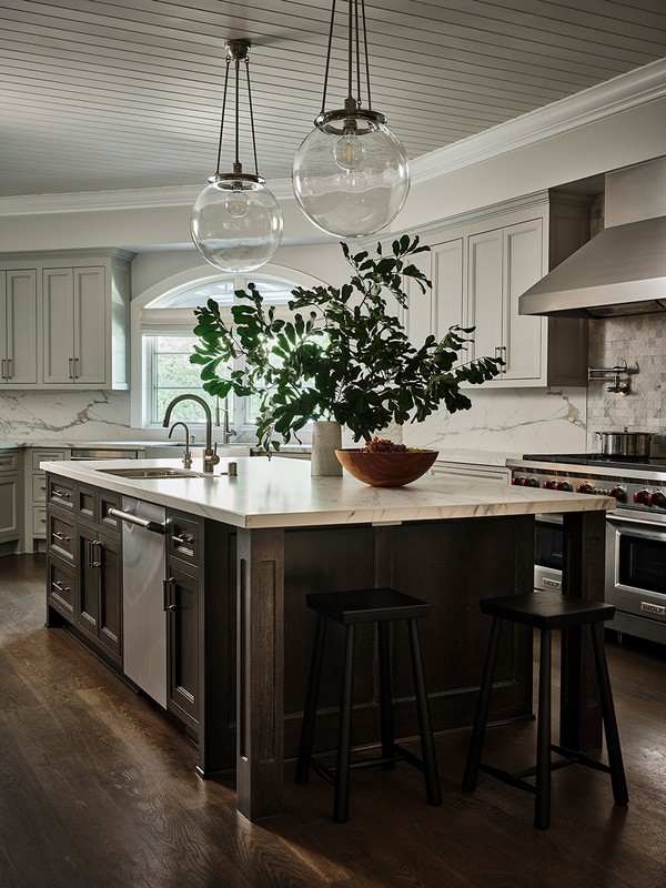 Kitchen interior featuring a marble countertop island with dark wood cabinetry, two black stools, and glass pendant lights.