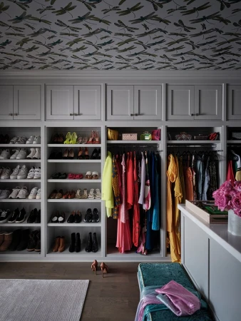 Bright, well-organized walk-in closet with custom shelving for shoes and clothes. A stylish storage space for fashion apparel.