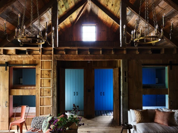 Rustic interior featuring wooden beams, vintage chandeliers, and a chair, creating a cozy and inviting space with a blend of natural and antique elements.