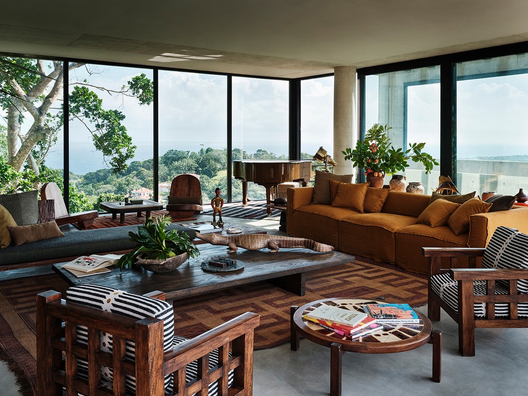 Living room interior showcasing a modern design with a large window offering a view of a lush green landscape and distant ocean.