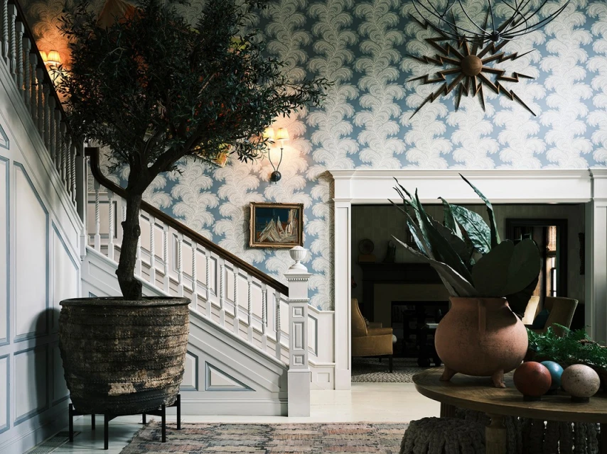 Ornate home interior with a large potted tree, decorative wallpaper, a staircase, and interior design elements.