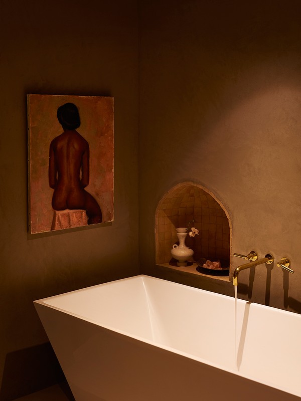 Bathtub in a modern interior with a painting on the wall. The design features a white bathtub, neutral walls and artistic decor.