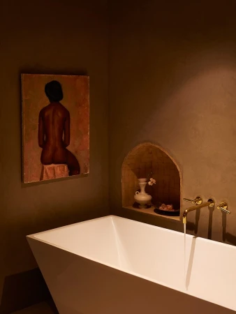 Bathtub in a modern interior with a painting on the wall. The design features a white bathtub, neutral walls and artistic decor.