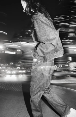 Model in denim jacket and jeans walking through a city street with motion blur effects in black and white