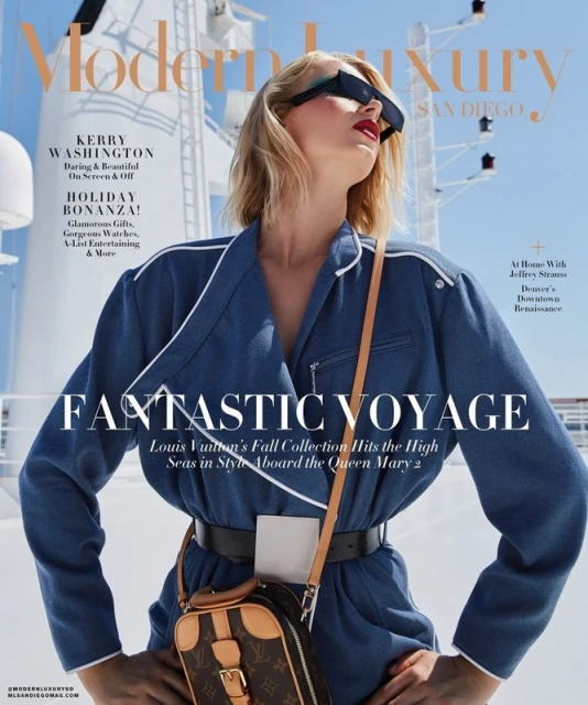 Modern Luxury magazine cover featuring a blond woman in a blue jumpsuit, shot on a cruise ship with blue sky background. Fashion editorial.