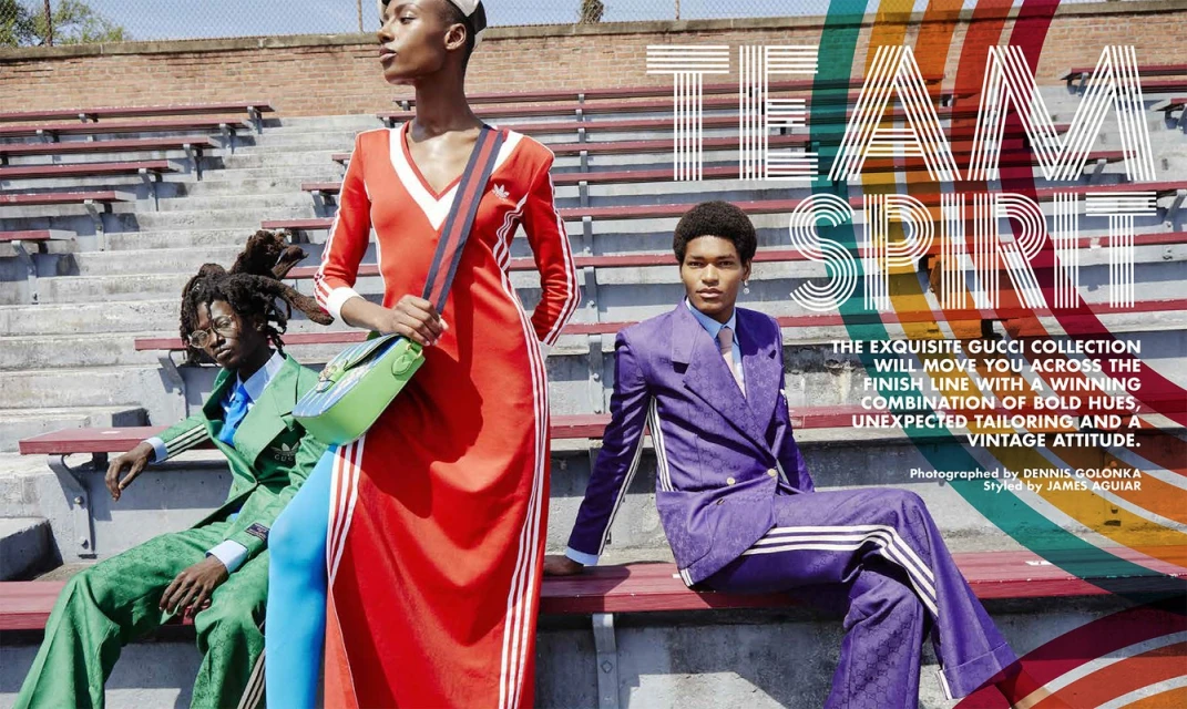 Three fashion models pose on bleachers in color-coordinated outfits; one wears a red dress, one a green suit, and one a purple suit.