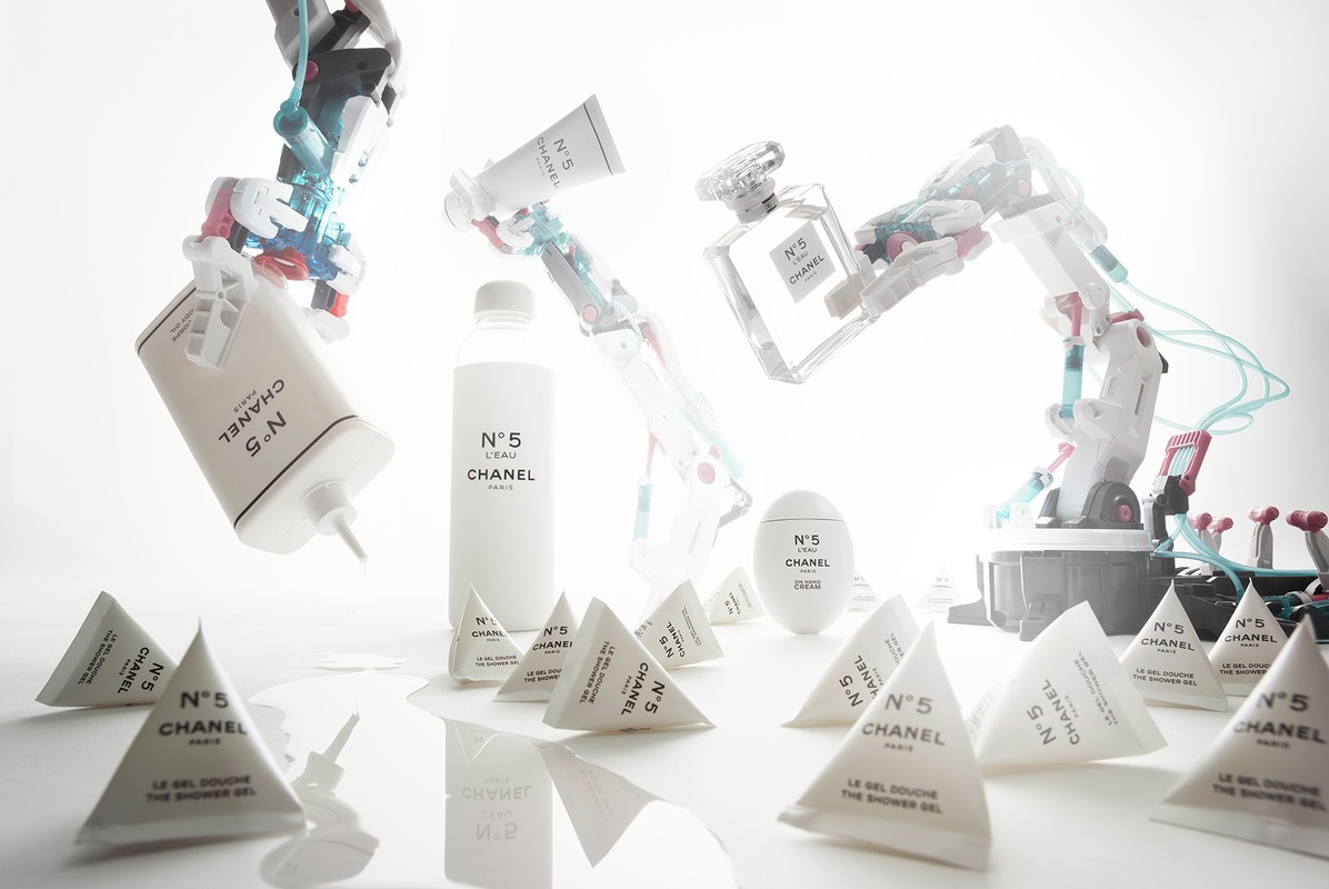 Shot of Chanel N°5 product collection with robot arms on white backdrop. Cosmetics include perfume, shower gel, lotion, body cream, and robot arms.