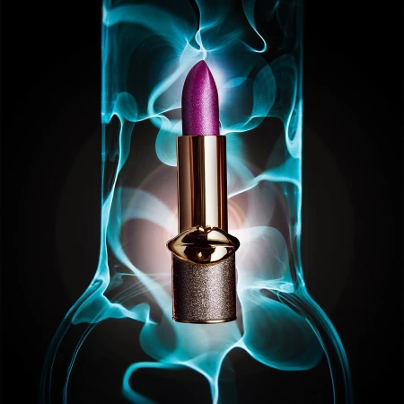 Close-up shot of a purple lipstick tube in front of blurred blue and white background, product shot for beauty or cosmetic.