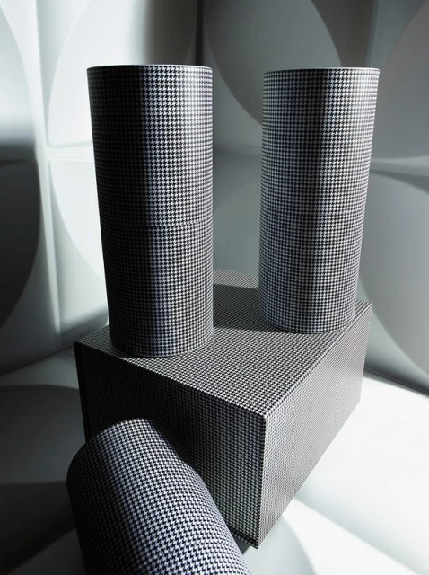 Geometric product shot featuring three cylinders and a rectangle covered in houndstooth pattern set against a white patterned background.