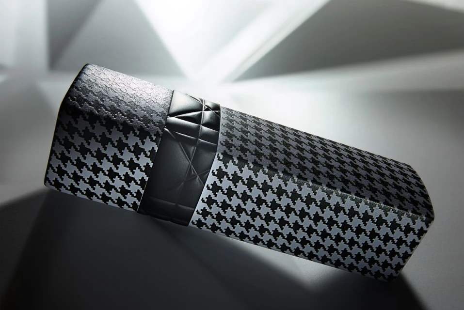 Houndstooth patterned product box with black quilted top detail against a white and gray gradient background, angled light and shadows.