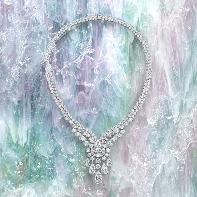 Elegant diamond necklace on a textured light blue, green, and purple background creating an eye-catching jewelry product shot.