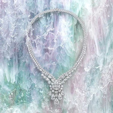 Elegant diamond necklace on a textured light blue, green, and purple background creating an eye-catching jewelry product shot.