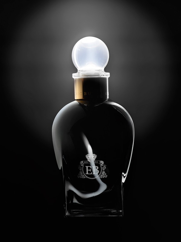 Elegant perfume bottle with a glowing sphere-shaped stopper against a dark backdrop, creating a luxurious and modern aesthetic.