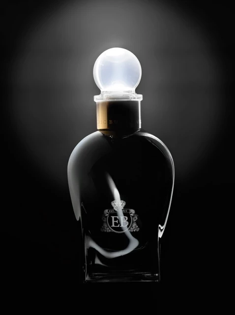 Elegant perfume bottle with a glowing sphere-shaped stopper against a dark backdrop, creating a luxurious and modern aesthetic.